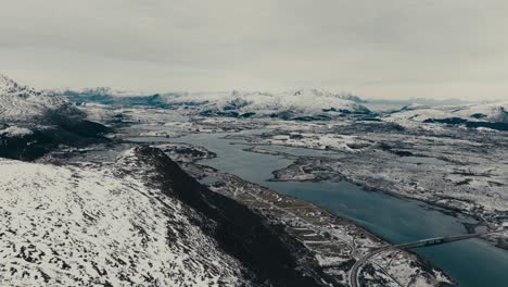 stunning winter landscape of lofoten islands with road bridge spanning the fjord in norway. - aerial shot
