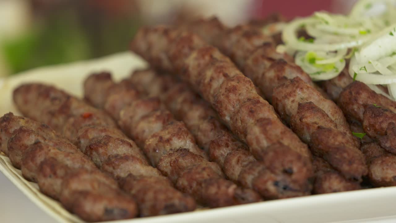Lula kebabı ve taze sebzelerle servis edilen yemek masası