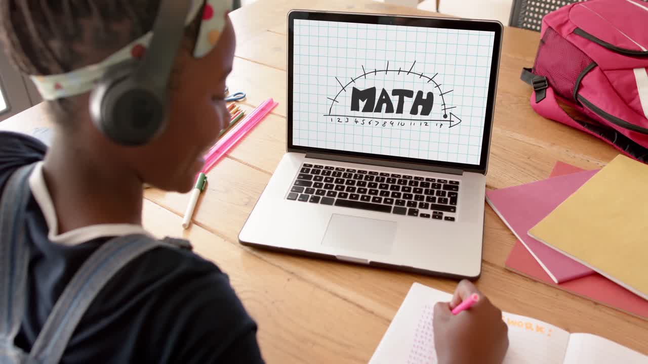 Happy african american schoolgirl having class on laptop video call with math text in slow motion