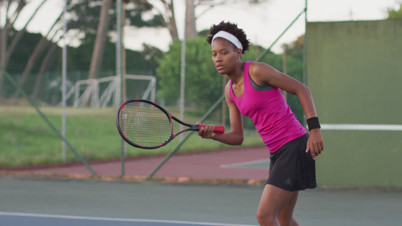 Video of focused african american female tennis player holding racket and hitting ball