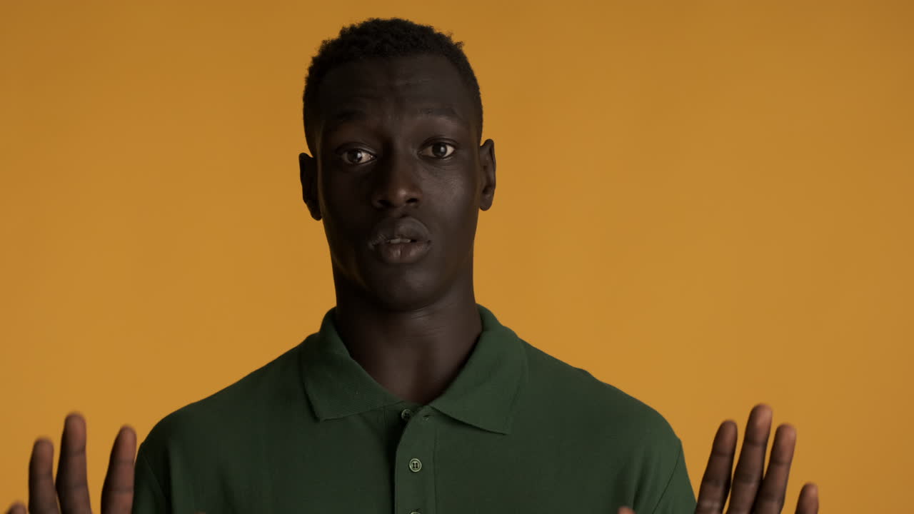 Scared African american man on yellow background.