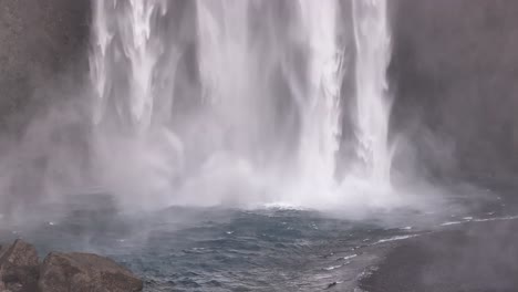 skógafoss waterfall impact zone splashing into clear pool in south iceland