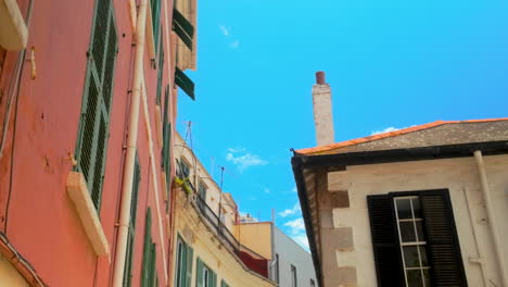 low-angle view of a quaint street in gibraltar, featuring traditional buildings with shutters, under a bright blue sky