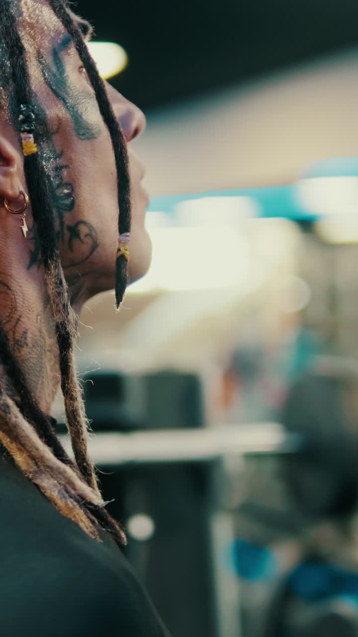 Close-up of a Tattooed Man with Dreadlocks in a Gym