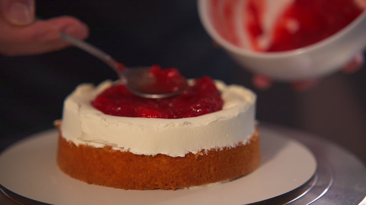 Close-up of Hand Decorating Cake with Red Fruit Topping and Cream