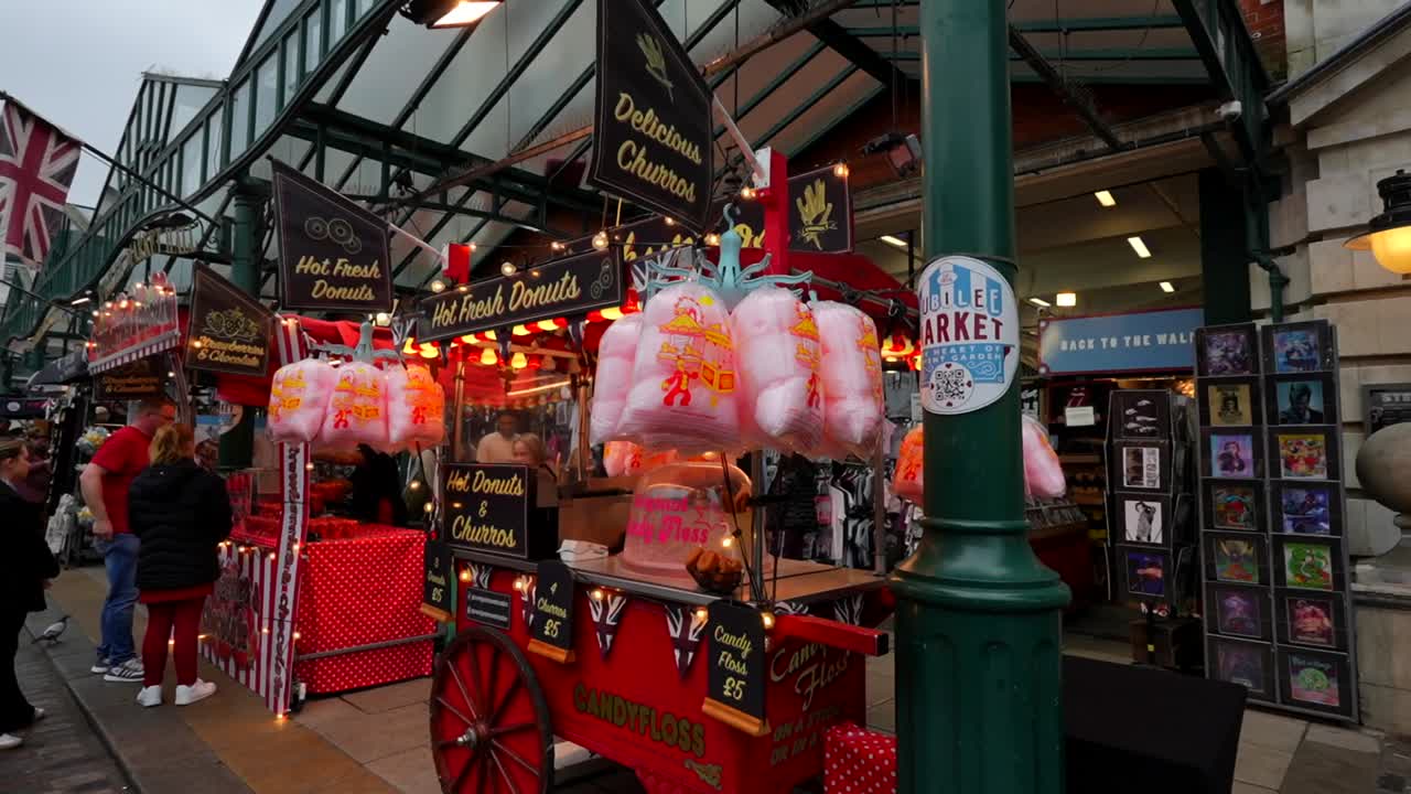 Candyfloss and donut stall at Covent Garden’s Jubilee Market with people browsing nearby