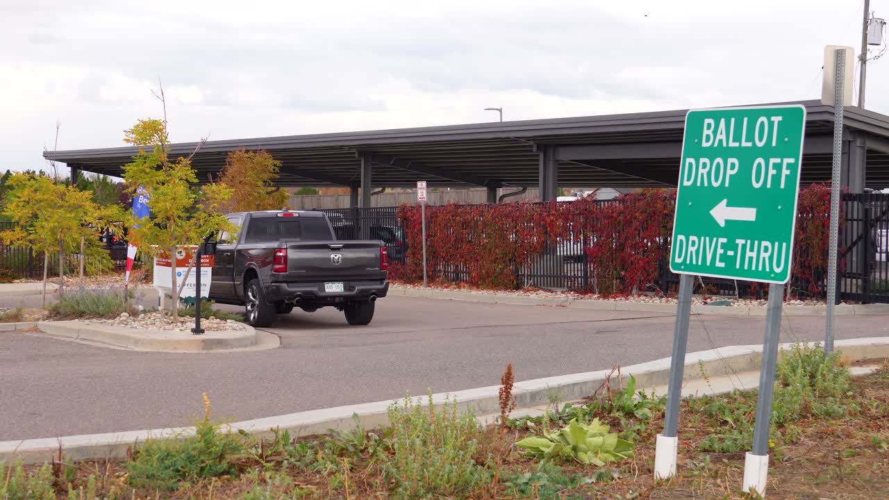 A man drops his ballot into an official secure box from his vehicle, representing civic engagement, democratic participation, freedom, safety, election security, equal access, responsibility to vote