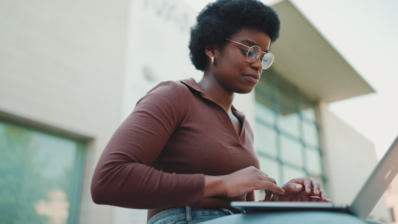 Beautiful female freelancer typing using laptop for work outdoors