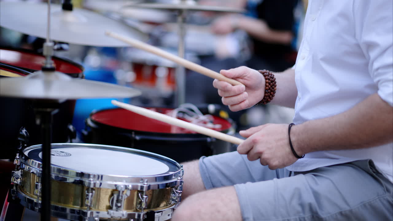 Close up of man playing red drums outside