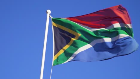 bandera sudafricana ondeando en el viento bajo un cielo azul en cámara lenta