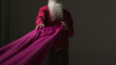 man with long white beard holds purple fabric