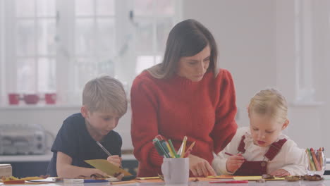 Mother-With-Children-At-Home-Doing-Craft-And-Making-Picture-From-Leaves-In-Kitchen