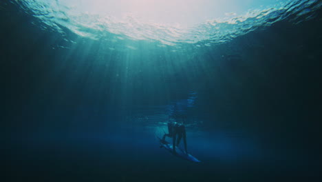 Surfer-pushes-board-underwater-to-escape-powerful-vortex-and-getting-caught-over-the-falls-of-wave,-silhouette