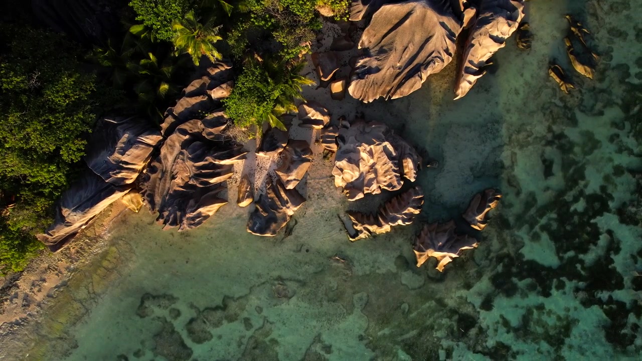 Pantai granit Anse Source D'Argent bersinar saat matahari terbenam. Udara