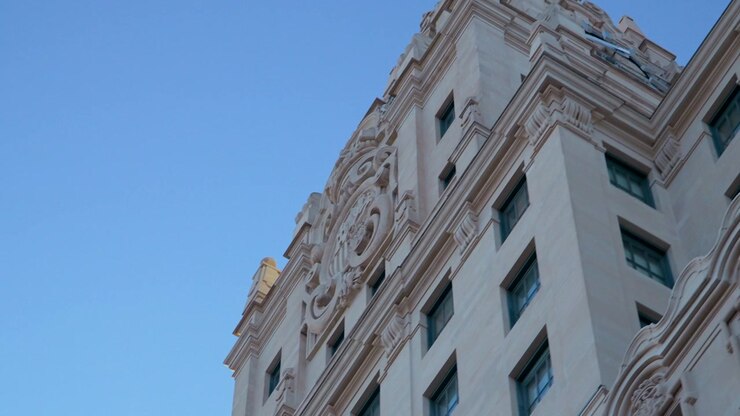 Inquadratura dal basso della facciata ornata e della torre dell'orologio di un edificio storico a Madrid, Spagna, che mostra dettagli architettonici classici contro un cielo sereno