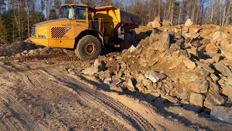 larger commercial dump truck, pile of dirt and stones for foundation materials