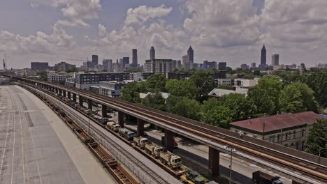 Atlanta-Georgia-Aerial-v909-drone-flyover-Husley-Yard-towards-O4W,-capturing-military-vehicles-loaded-on-railway-transport-and-downtown-cityscape-on-the-skyline---Shot-with-Mavic-3-Pro-Cine---May-2023