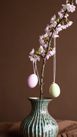 easter decoration with cherry blossoms and pastel eggs in a vase