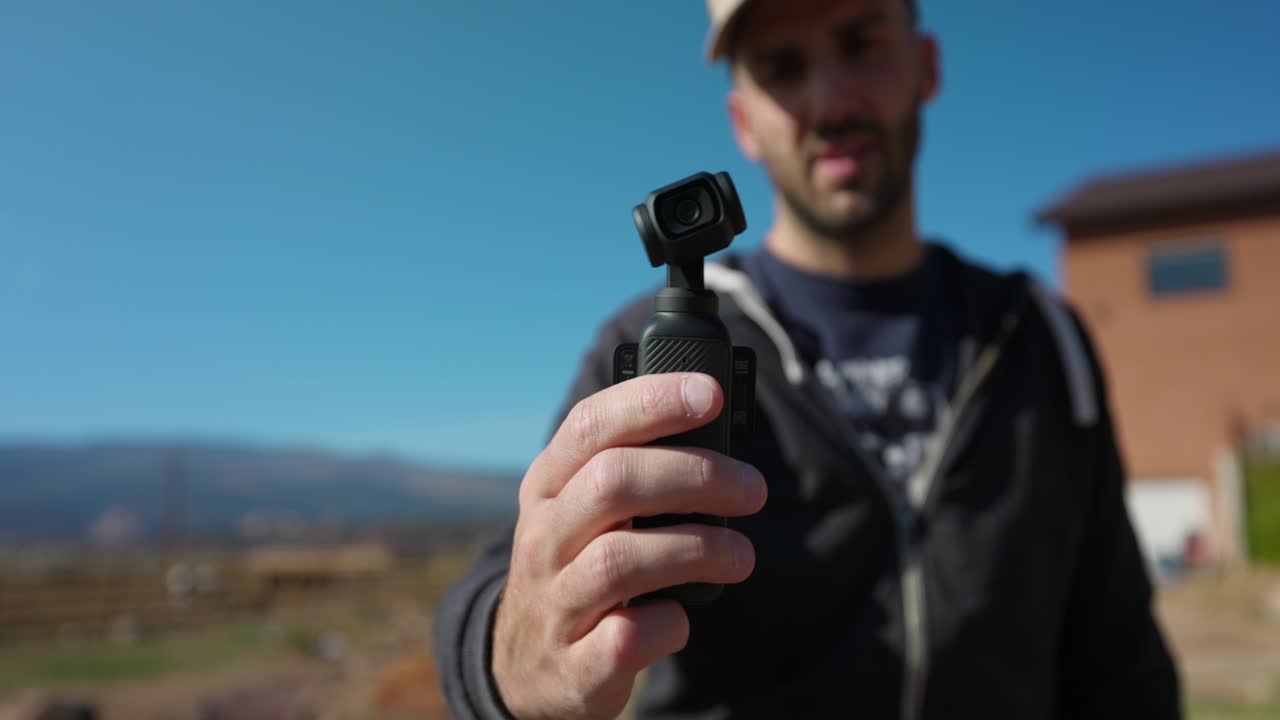 vista en primer plano de dji osmo bolsillo 3 siendo sostenido y operado por un hombre al aire libre para vlog