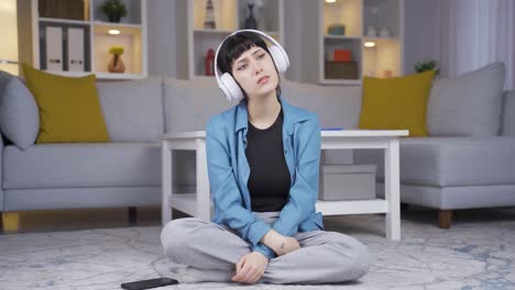 young woman listening to music with headphones is unhappy and sad.