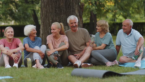 portrait of joyous fitness coach and senior people in park