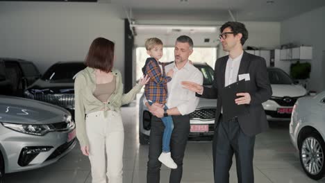 A-family-of-a-middle-aged-man-his-wife-and-little-son-came-to-a-car-dealership-and-talked-with-an-assistant-in-a-business-suit-about-what-cars-were-available-and-about-the-cars-in-a-modern-car-dealership