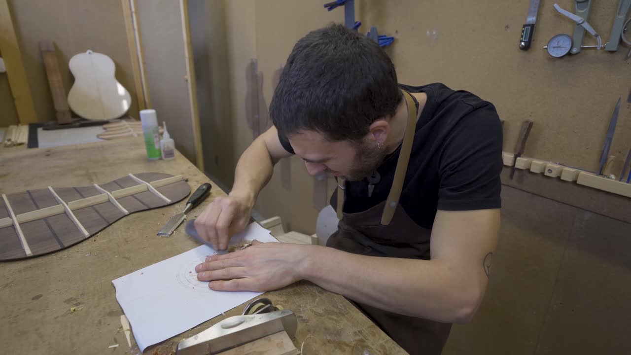 artesano aplanando una pieza de madera con un raspador en el taller