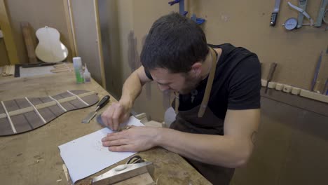 artesano aplanando una pieza de madera con un raspador en el taller