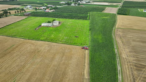 aerial shot of a combine harvester working in a wheat field next to a green orchard, showcasing the efficient division of farmland and the use of modern agricultural machinery