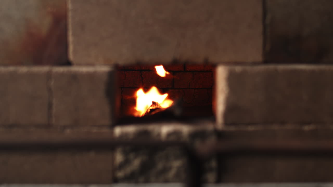 장갑을 낀 손이 집게를 용광로에 넣어 대장간을 예열하기 시작합니다.