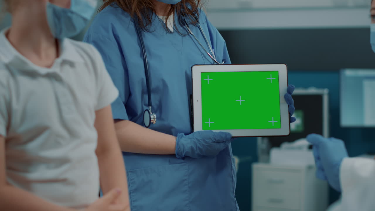 Medical professionals holding a tablet with a green screen