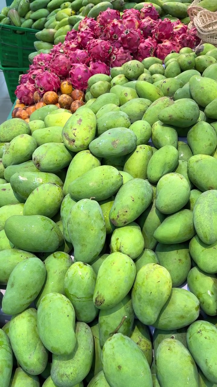 Manghi verdi freschi e frutto del drago esposti in un mercato