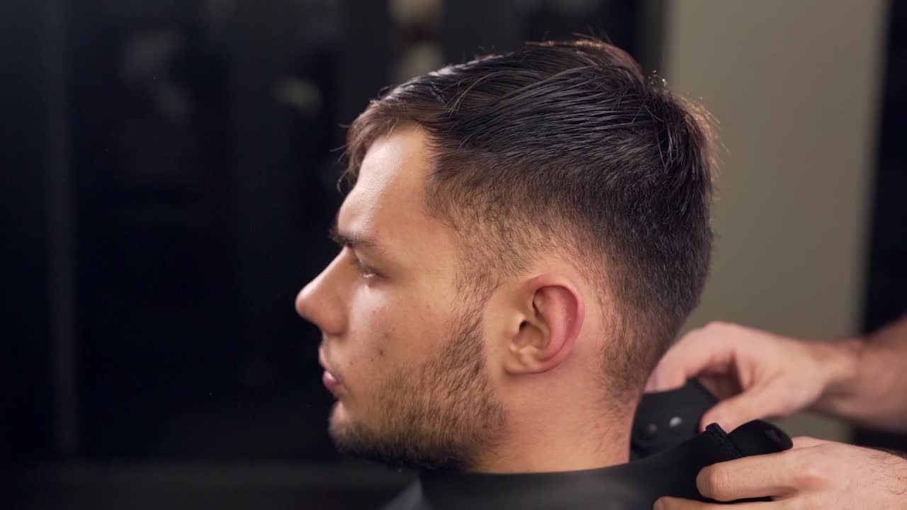 nærbillede af frisøren, der lægger en kappe på klienten før frisuren