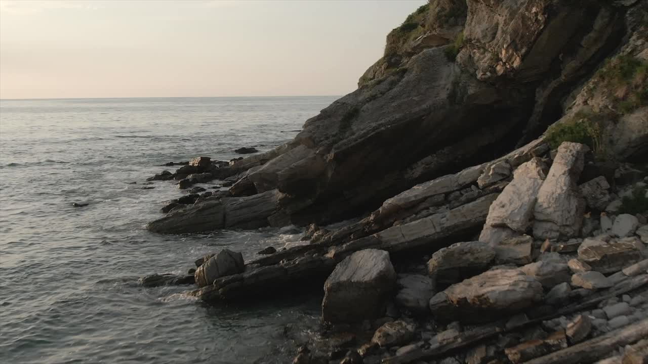 Drone flying at low altitude along rocky cliff at dusk, Hendaye, Pyrénées-Atlantiques, France. Aerial