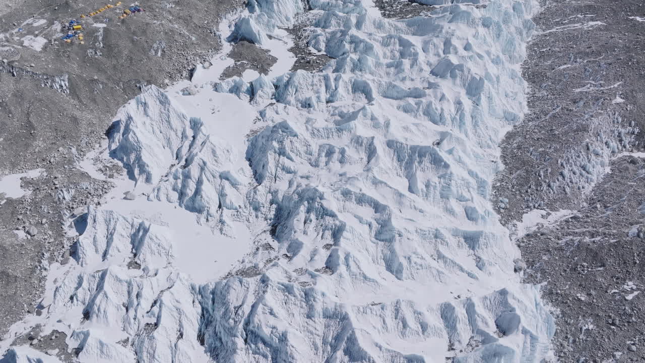 Top-down drone shot of Everest Base Camp and Khumbu Glacier in Nepal, showing dense snow, dry lands, high-altitude tents, Sagarmatha peaks, and visible trail pollution for climbers in Himalayas