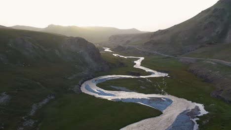 aerial shot flying over the kurumduk river in kyrgyzstan, into the sun