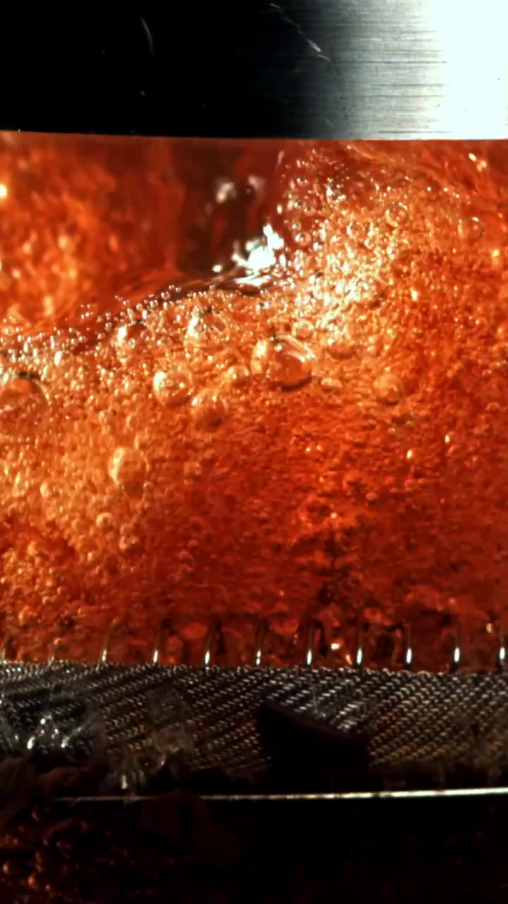 Primo piano di liquido ambrato gassato con bollicine che salgono