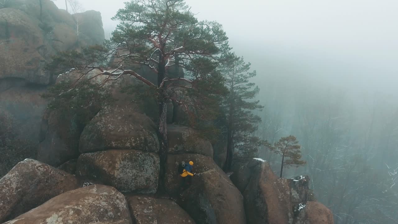 Person Climbing Rocks in Foggy Mountain Landscape