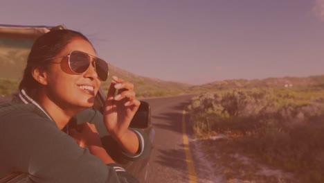 Animation-of-happy-biracial-woman-wearing-glasses,-driving-a-cabriolet