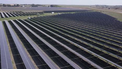 huge solar panel array in prairie field beside rural highway, aerial