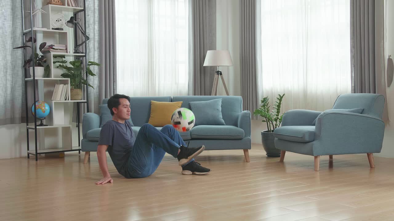 Man playing freestyle football in living room