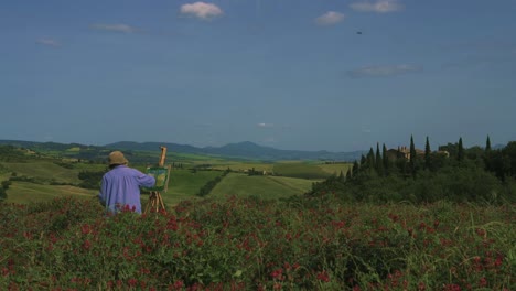 una anciana pintora está pintando la belleza natural del famoso val d&#39;orcia, también conocido como el valle de orcia como pintura, de pie en un campo de flores