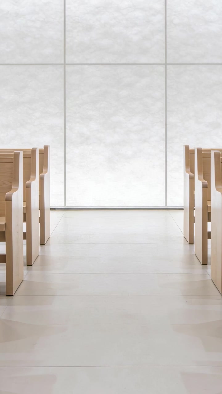 Vertical video: Panning camera revealing central aisle and wood pews in chapel, showing lit panels