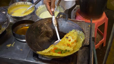 cooking omelette with vegi at asian street night market street food booth in hot summer local food