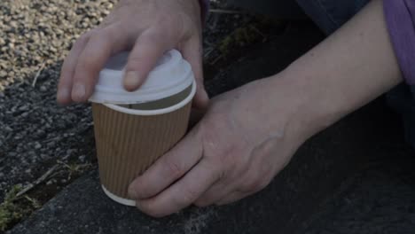 sitting on the sidewalk drinking takeout coffee close up shot