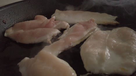 Chicken-Fillets-Cooking-in-Steaming-Black-Frying-Pan,-Closeup-Move-In