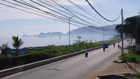 time-lapse of cars, scooters and trucks on busy waterfront road in the capital city dili, timor leste in south east asia, slow pan out