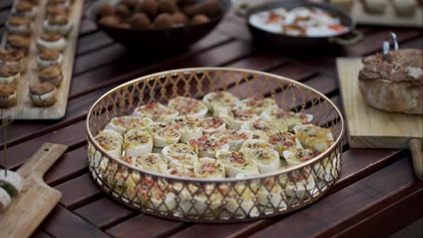 appetizer rolls topped with herbs and bacon bits displayed in an ornate golden tray