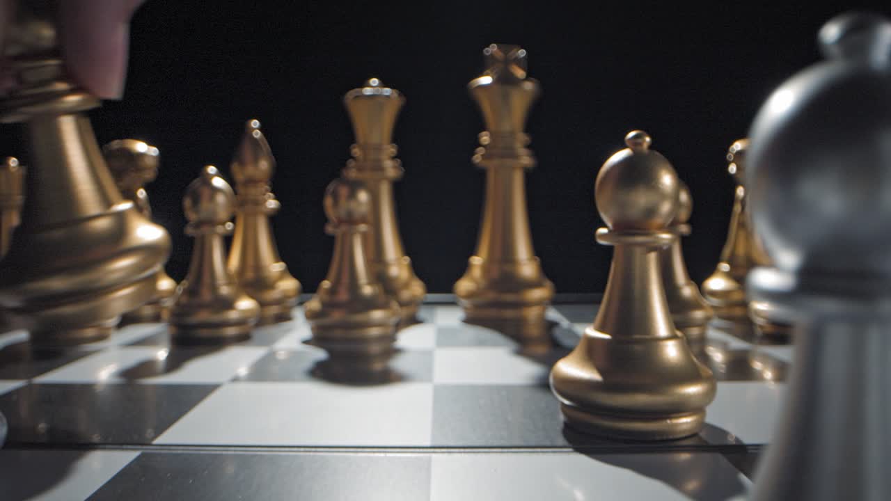 Shot pushing in through a chess set while a hand moves the enemy's bishop through frame