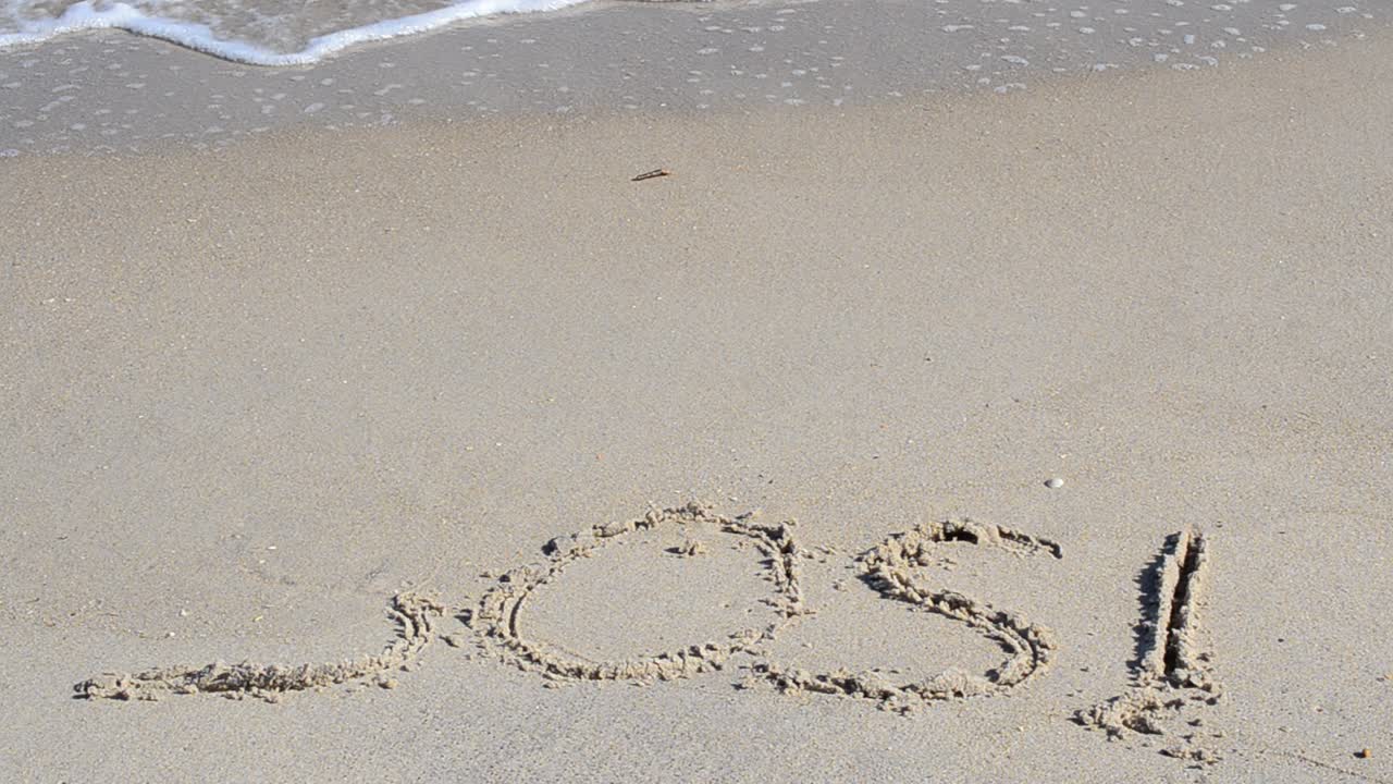 SOS-skilt skylles væk af en bølge. Et råb om hjælp på sandstranden